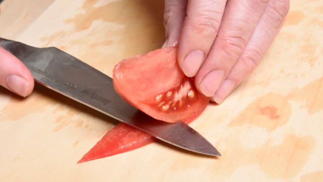 トマトのチューリップ切り2：まな板に置き、皮の尖った方から皮と果肉を切り離す