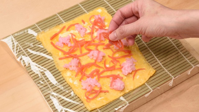 巻きすに薄焼き卵を1枚置き、桃色の酢飯半量と紅ショウガ半量を散らす