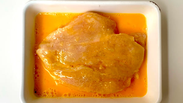 薄力粉を付けた鶏肉を溶き卵にくぐらせる