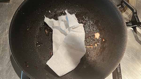 フライパンの余分な油を拭き取る