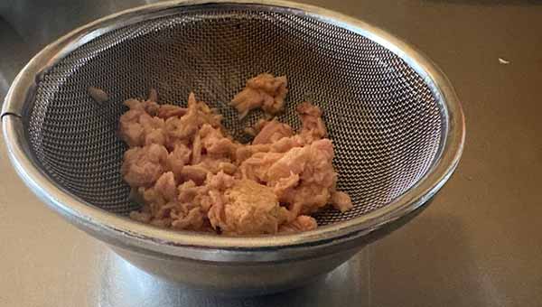 ツナ缶を金ザルにあけて油を切る