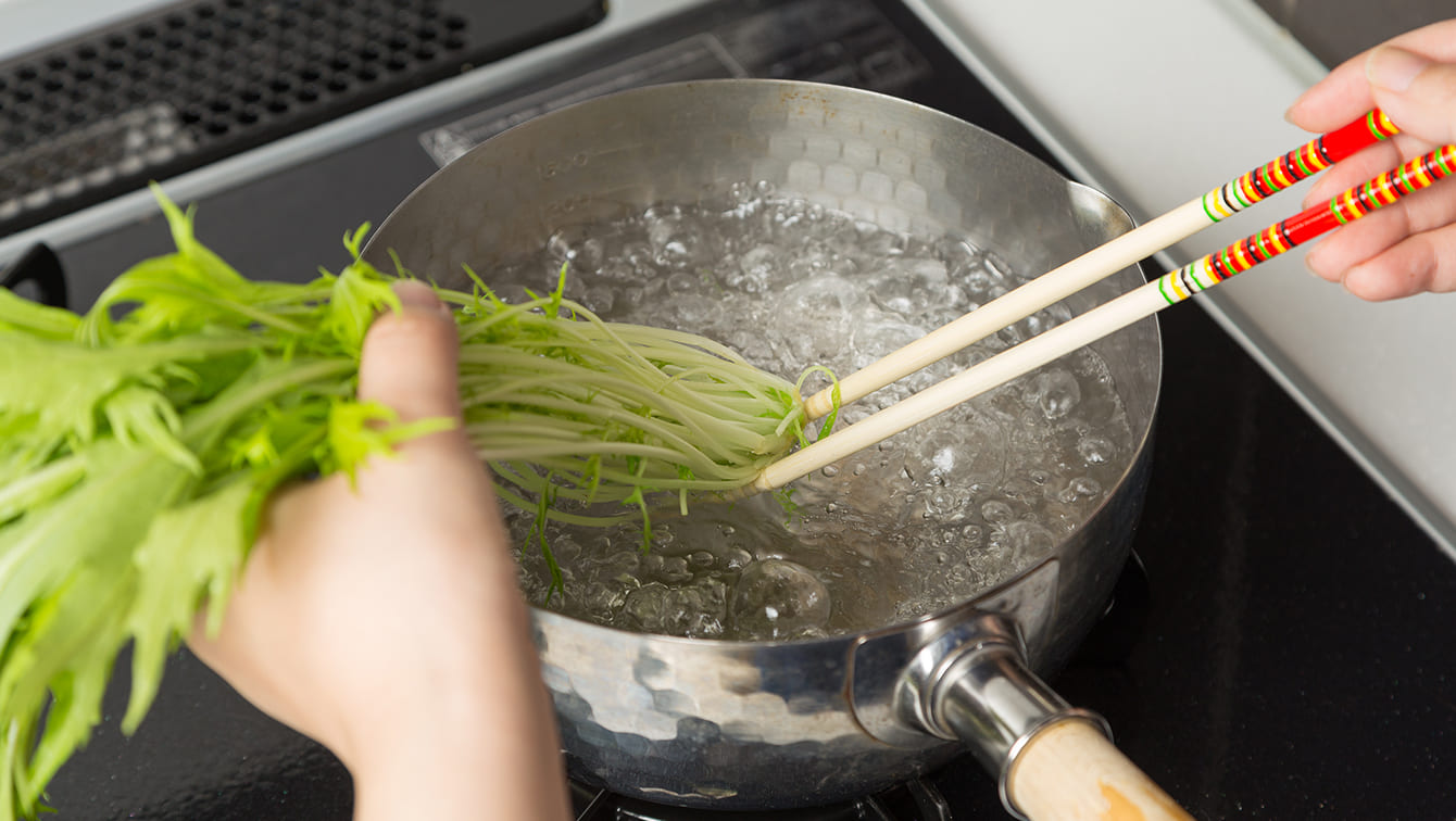 水菜の歯ごたえをほどよく残す湯通しの仕方：沸騰した湯に根元から入れ、やわらかくなったらすぐに葉先を沈め、5秒前後でざるに上げる